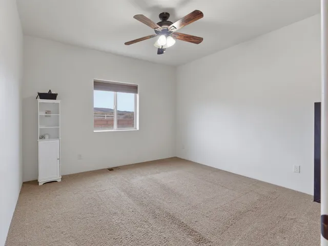 an empty room with a window and a ceiling fan
