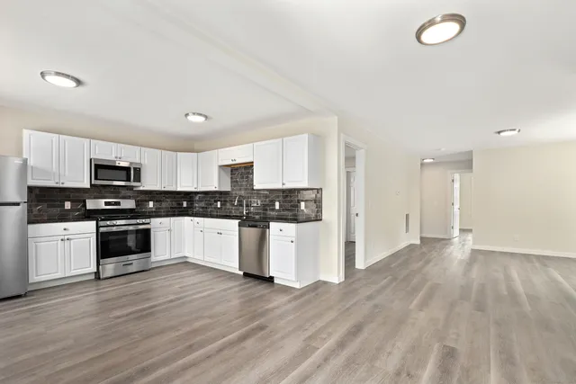 a kitchen with granite countertop a stove top oven and cabinets