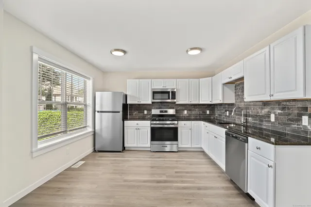 a kitchen with granite countertop a stove top oven sink and cabinets