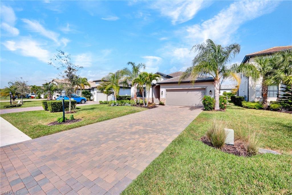 18298 Ridgeline Drive Estero, FL 33928 - Photo 7 of 49 View of front of house featuring decorative driveway, a front lawn, stucco siding, and a garage