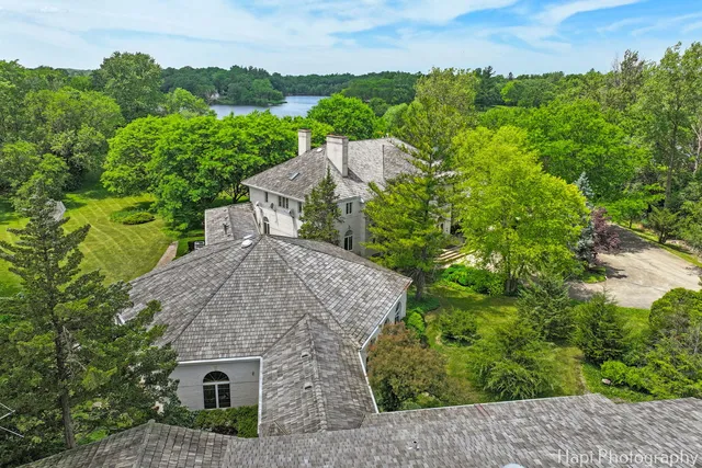 an aerial view of residential house with outdoor space and trees all around