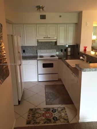 a kitchen with granite countertop a stove a sink and a refrigerator