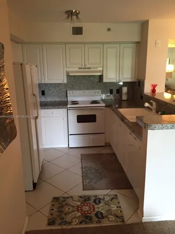 a kitchen with granite countertop a stove a sink and a refrigerator