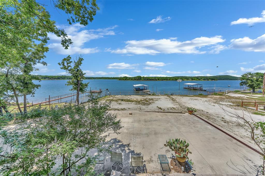 566 Selma Park Road Bowie, TX 76230 - Photo 22 of 40 Expansive lakefront property featuring extensive concrete paving, a fenced perimeter, and established landscaping