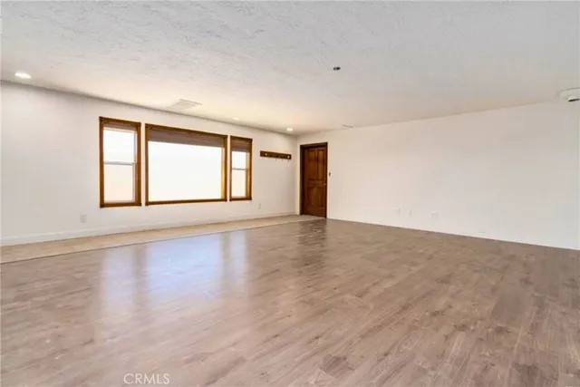 a view of an empty room with wooden floor and window