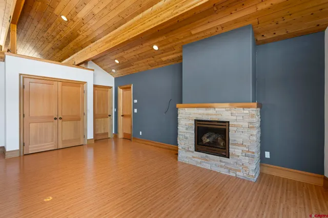a view of an empty room with wooden floor fireplace and a window