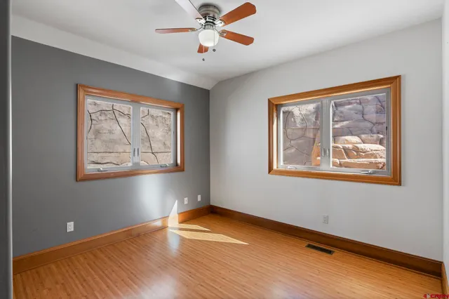 a view of empty room with wooden floor and fan