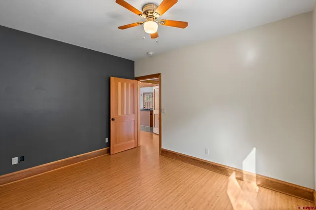 a view of an empty room with window and wooden floor