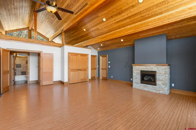 a view of an empty room with wooden floor fireplace and a window