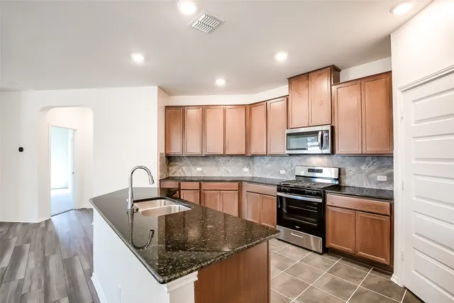 a kitchen with stainless steel appliances granite countertop a sink stove and cabinets