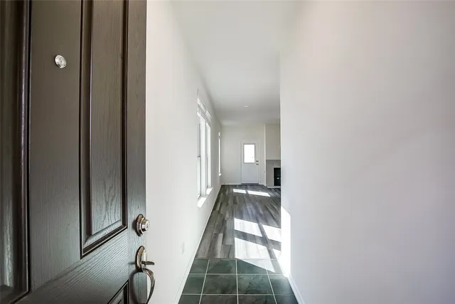 a view of a hallway with wooden floor and a bathroom