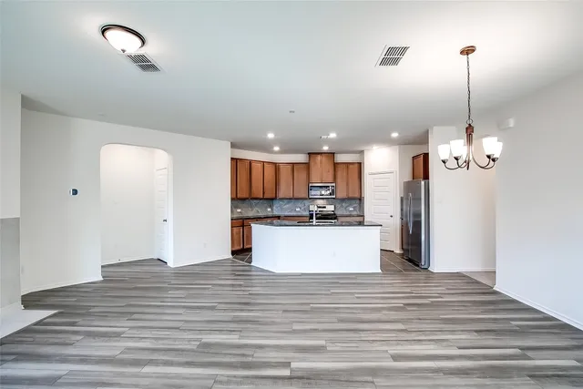 a large kitchen with kitchen island a refrigerator a stove a center island and wooden floor