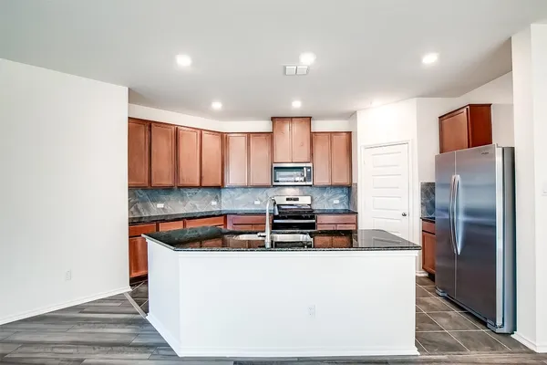 a kitchen with stainless steel appliances granite countertop a refrigerator a stove and a sink