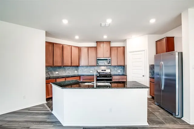 a kitchen with stainless steel appliances granite countertop a refrigerator a stove and a sink