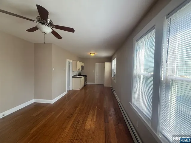 a view of a hallway with wooden floor and a ceiling fan