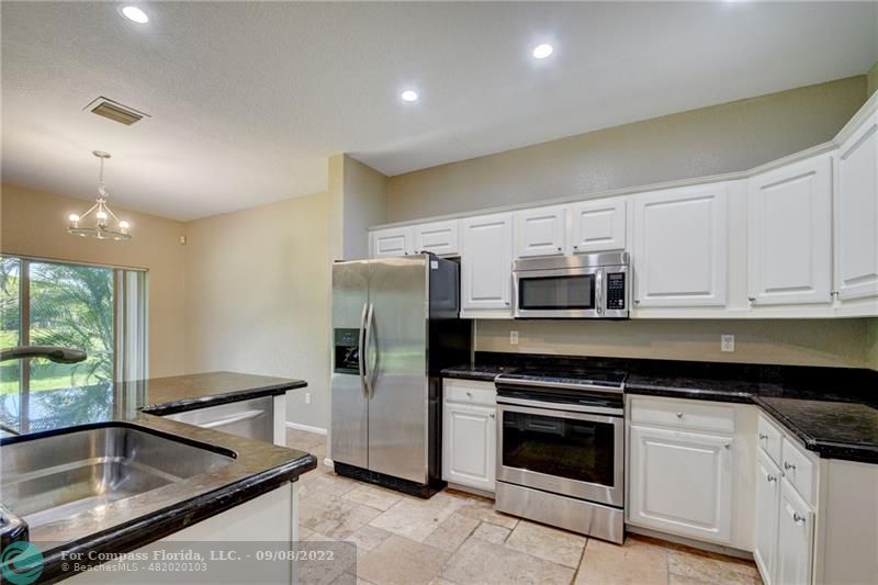 4375 Emerald Vista Lake Worth Beach, FL 33461 - Photo 5 of 27 a kitchen with stainless steel appliances granite countertop a stove a refrigerator and a sink