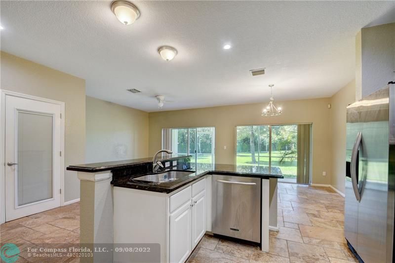 4375 Emerald Vista Lake Worth Beach, FL 33461 - Photo 6 of 27 a kitchen with granite countertop a stove a sink and a refrigerator