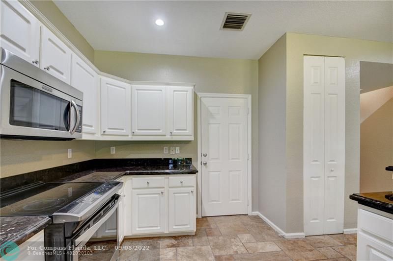 4375 Emerald Vista Lake Worth Beach, FL 33461 - Photo 7 of 27 a kitchen with stainless steel appliances granite countertop a stove a sink and a microwave