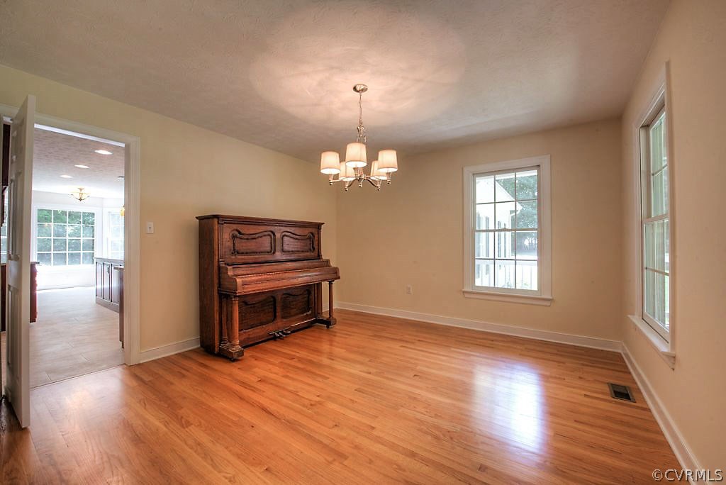 9217 Varina Road Henrico, VA 23231 - Photo 12 of 49 an empty room with wooden floor chandelier and windows