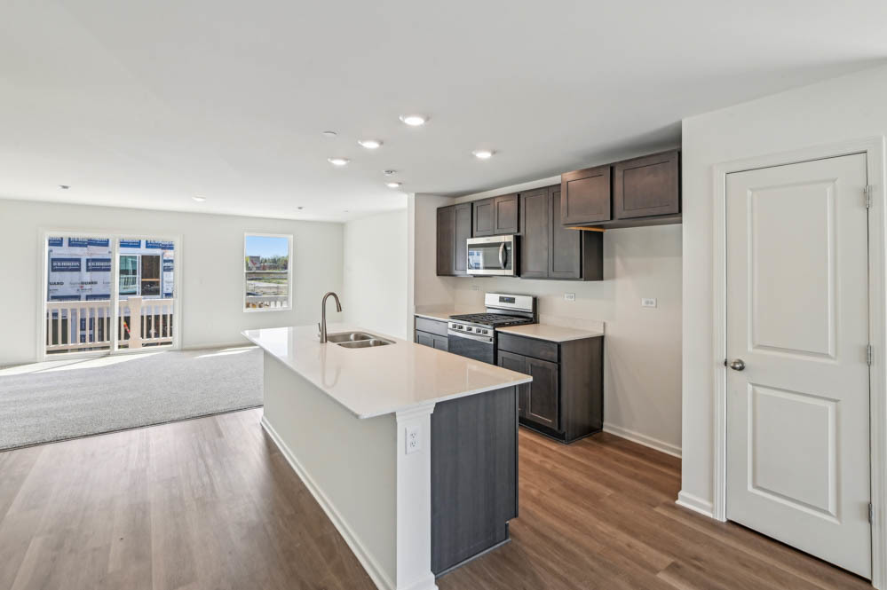 17305 Ulster Drive Tinley Park, IL 60477 - Photo 4 of 25 a large kitchen with kitchen island a sink a stove a refrigerator cabinets and a wooden floor