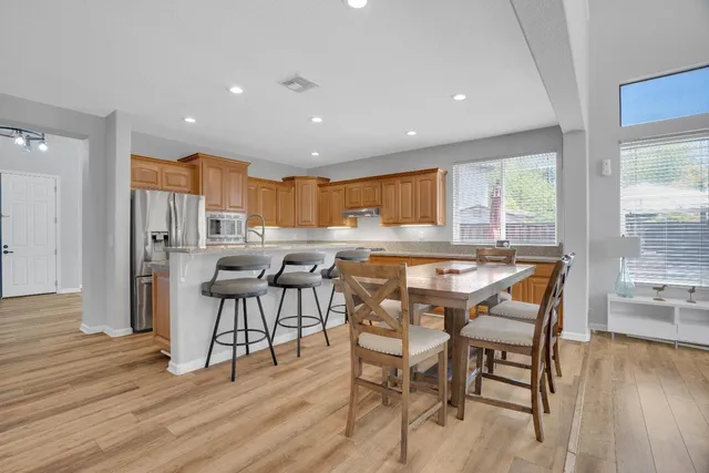 a dining room with stainless steel appliances furniture large window and wooden floor