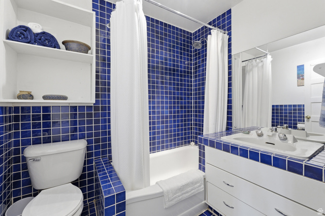 365 North Main Street Fillmore, UT 84631 - Photo 23 of 51 Bathroom featuring floor-to-ceiling blue square tile, white bathtub, built-in storage shelving, a vanity with integrated sink, and a large wall-mounted mirror