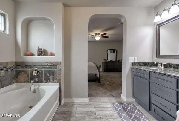 a bathroom with a tub a sink and mirror
