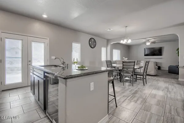a view of a dining room with furniture a chandelier and kitchen view