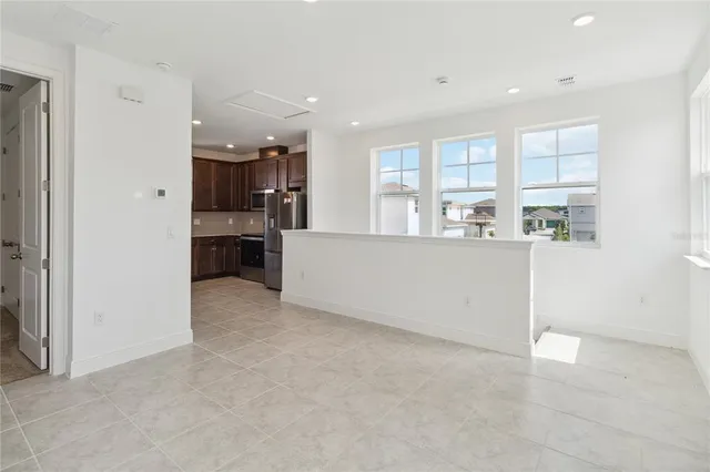 a living room with stainless steel appliances kitchen island granite countertop a refrigerator and cabinets