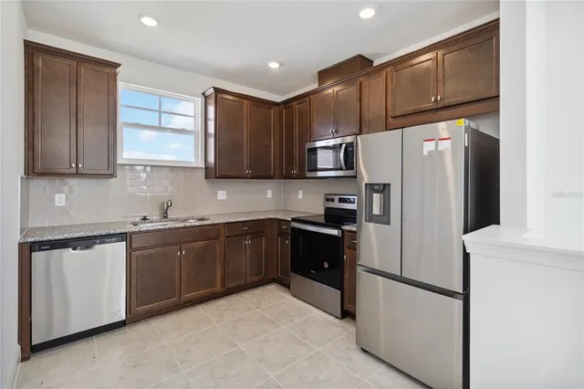 a kitchen with granite countertop a refrigerator and a sink