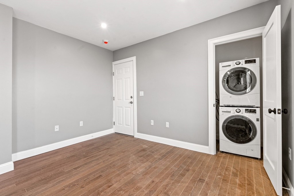 17-19 Spring Garden Street Boston, MA 02125 - Photo 11 of 24 a view of a hallway with wooden floor and a washer dryer
