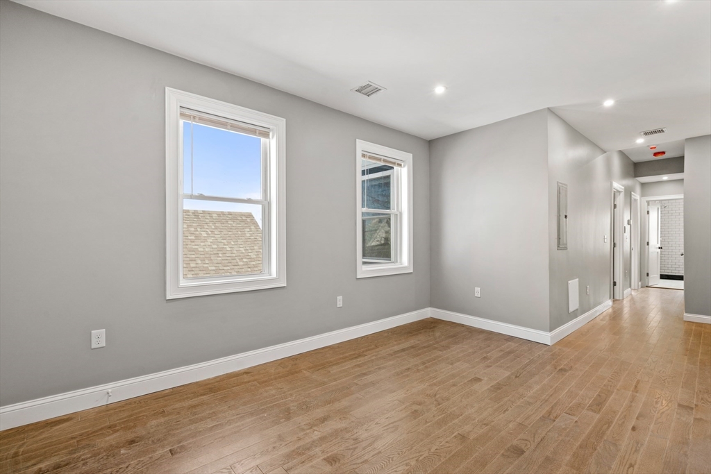17-19 Spring Garden Street Boston, MA 02125 - Photo 14 of 24 an empty room with wooden floor and windows