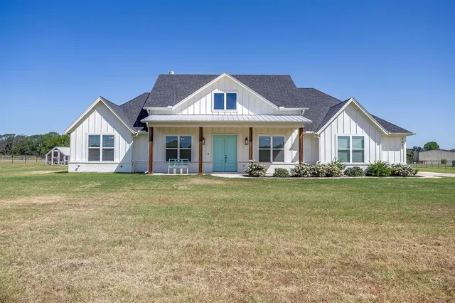 a view of a house with a big yard and large trees