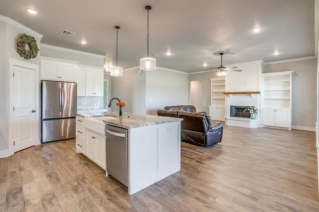 a kitchen with stainless steel appliances granite countertop a refrigerator a stove a sink and a fireplace