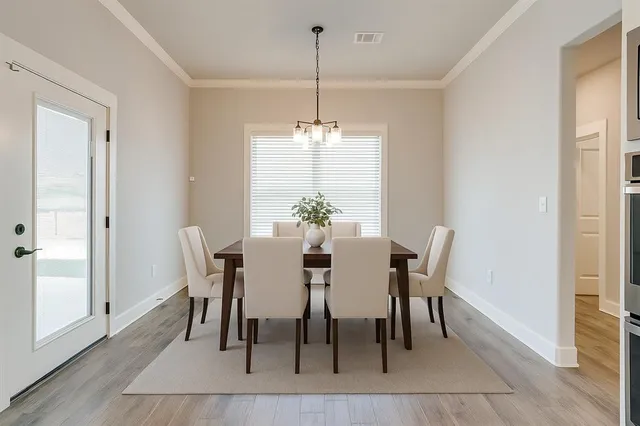 a dining room with furniture wooden floor a potted plant and a chandelier