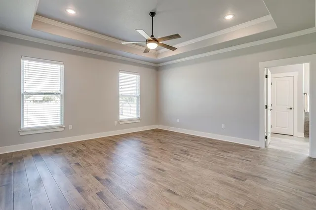 an empty room with wooden floor chandelier and windows