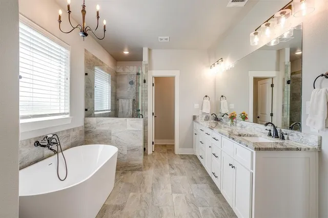 a bathroom with a double vanity sink a mirror a bathtub and shower