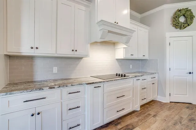 a kitchen with granite countertop white cabinets and stainless steel appliances