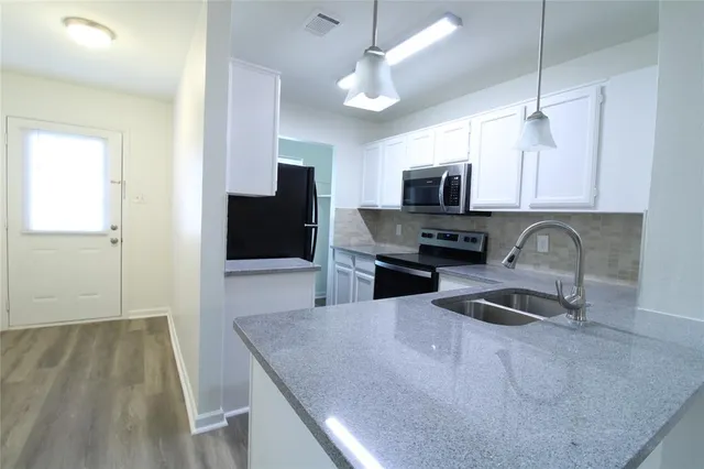 a kitchen with granite countertop a stove a microwave a sink a refrigerator and island