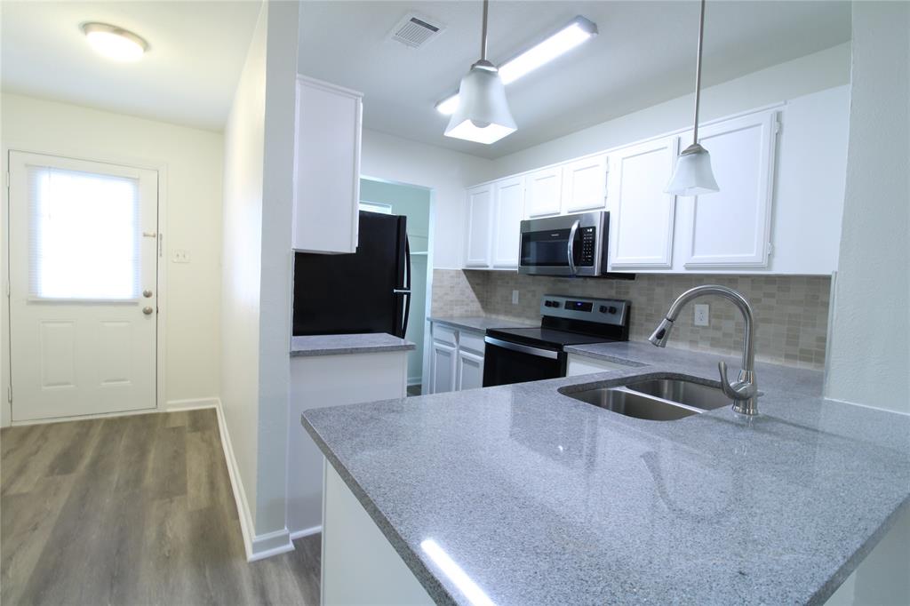 605 Carriagehouse Lane, Unit B2 Garland, TX 75040 - Photo 2 of 11 a kitchen with granite countertop a stove a microwave a sink a refrigerator and island