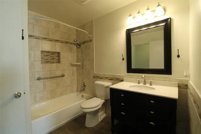 a bathroom with a sink vanity mirror bathtub and toilet