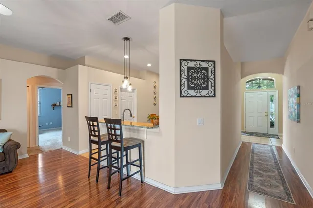 a view of a hallway with wooden floor table and chairs