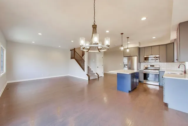 a open kitchen with stainless steel appliances kitchen island granite countertop a sink dishwasher a living room with couches and kitchen view
