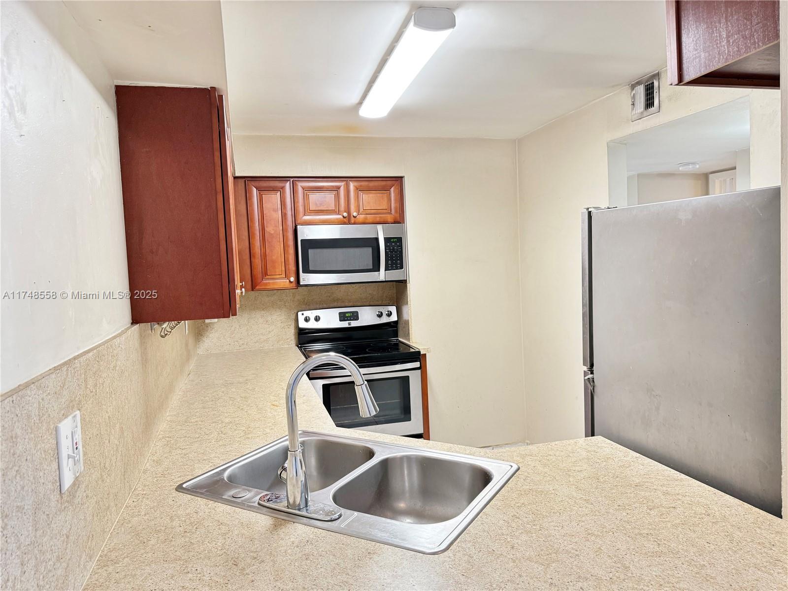 Tamiami Miami, FL 33184 - Photo 10 of 27 a kitchen with stainless steel appliances a sink a stove a microwave a counter top space and cabinets