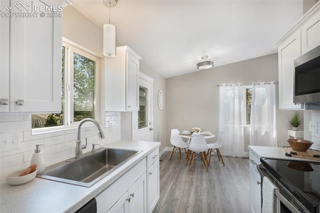 624 Wheat Field Road Fountain, CO 80817 - Photo 10 of 26 Kitchen featuring light hardwood / wood-style floors, sink, a healthy amount of sunlight, and decorative backsplash