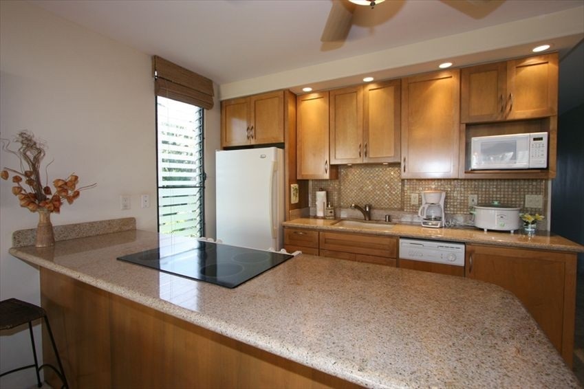998 South Kihei Road, Unit 205 Kihei, HI 96753 - Photo 10 of 12 a kitchen with kitchen island a counter top space a sink stainless steel appliances and cabinets