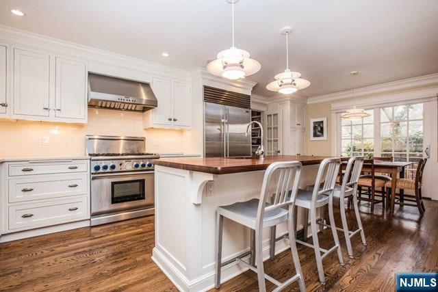 10 Orchard Place Tenafly, NJ 07670 - Photo 4 of 25 a kitchen with stainless steel appliances kitchen island granite countertop a stove a oven a dining table and chairs with wooden floor