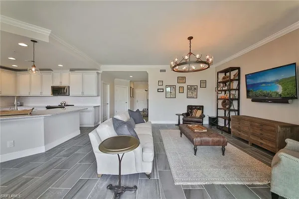 a living room with furniture kitchen view and a chandelier