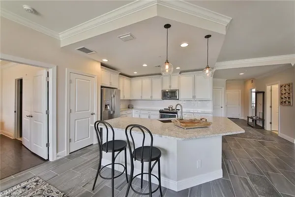 a kitchen with stainless steel appliances granite countertop a stove a refrigerator a sink a dining table and chairs with wooden floor