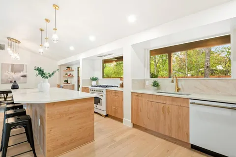 a kitchen with counter top space sink and living room view